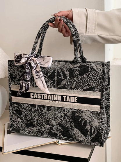 Handbag with black and white pattern and 'Castrainh Tade' branding held by a person.