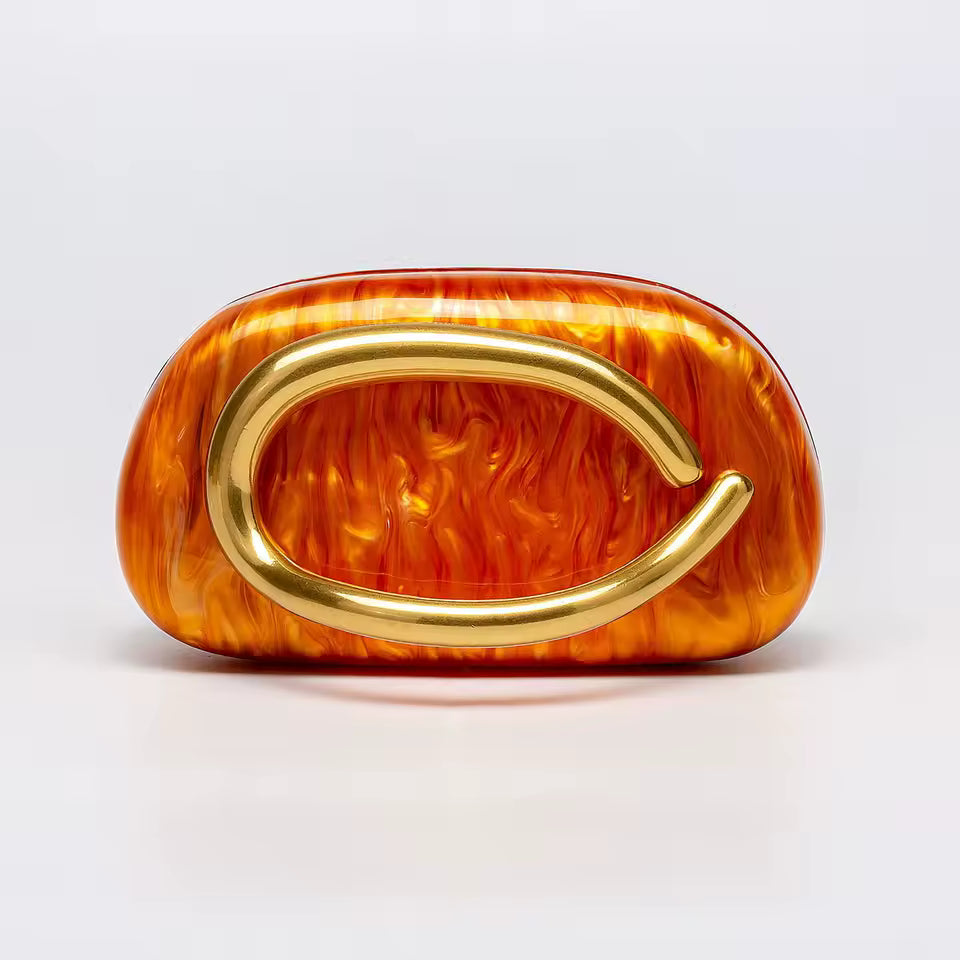 Orange flame-patterned clutch with gold handle on a light gray background