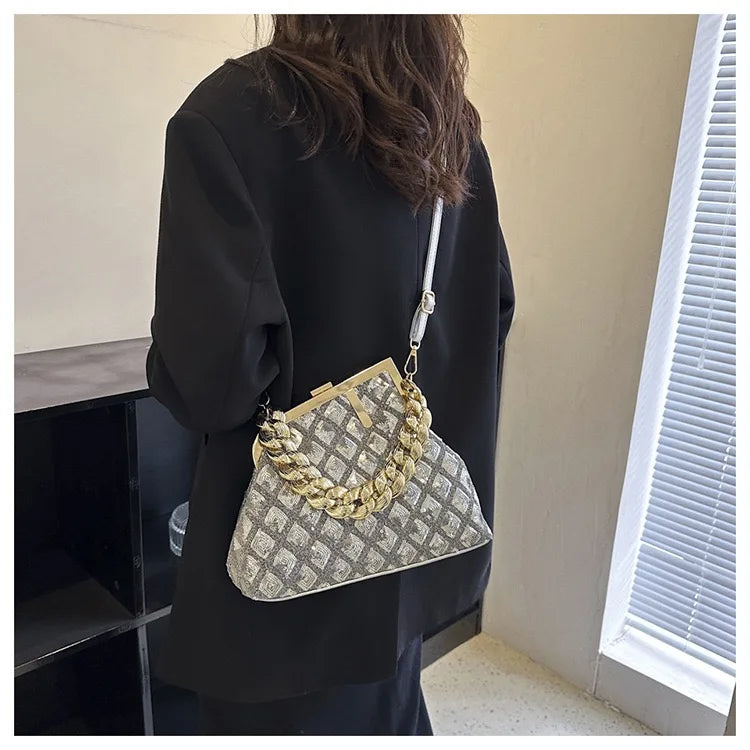 Person holding a silver handbag with a chain detail indoors.