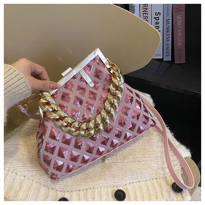 Pink and gold handbag held by a person wearing a beige sweater.