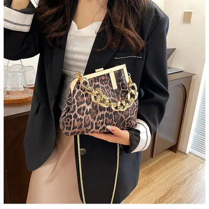 Person holding a Carauana_UNIU_Leopard_Clutch with gold chain detail indoors.