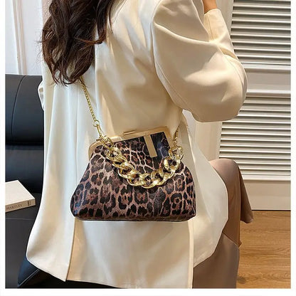 Person holding a Carauana_UNIU_Leopard_Clutch with gold chain detail
