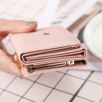Pink wallet held by a hand on a white and gray checkered surface