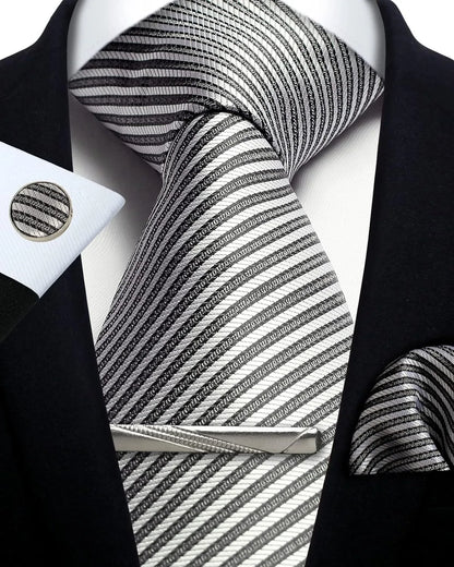 Black and white striped tie with matching cufflinks and tie clip on a black suit jacket.