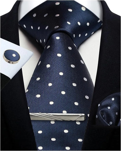 Navy blue tie with white polka dots, silver tie clip, and matching pocket square on a suit.
